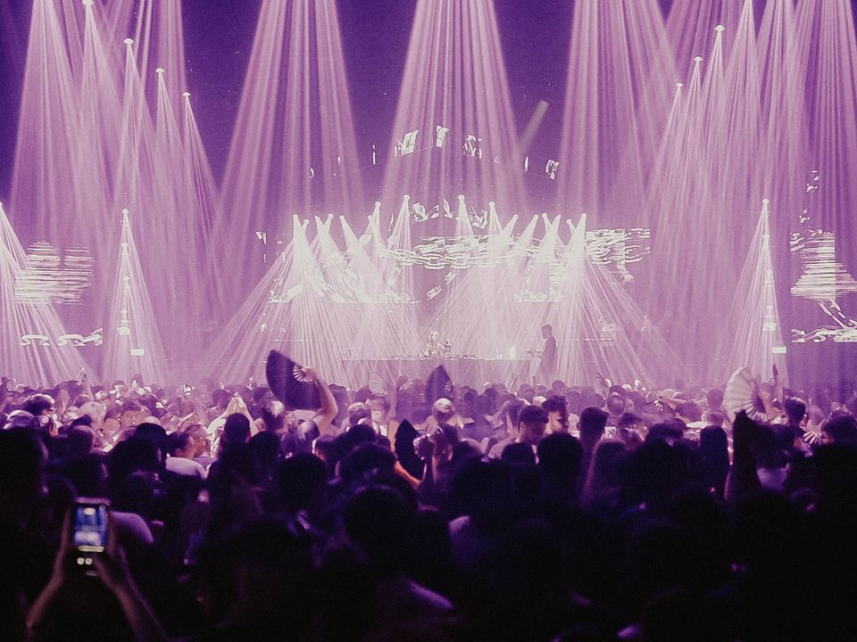 Stage with dozens of purple beams and LED visuals over the crowd