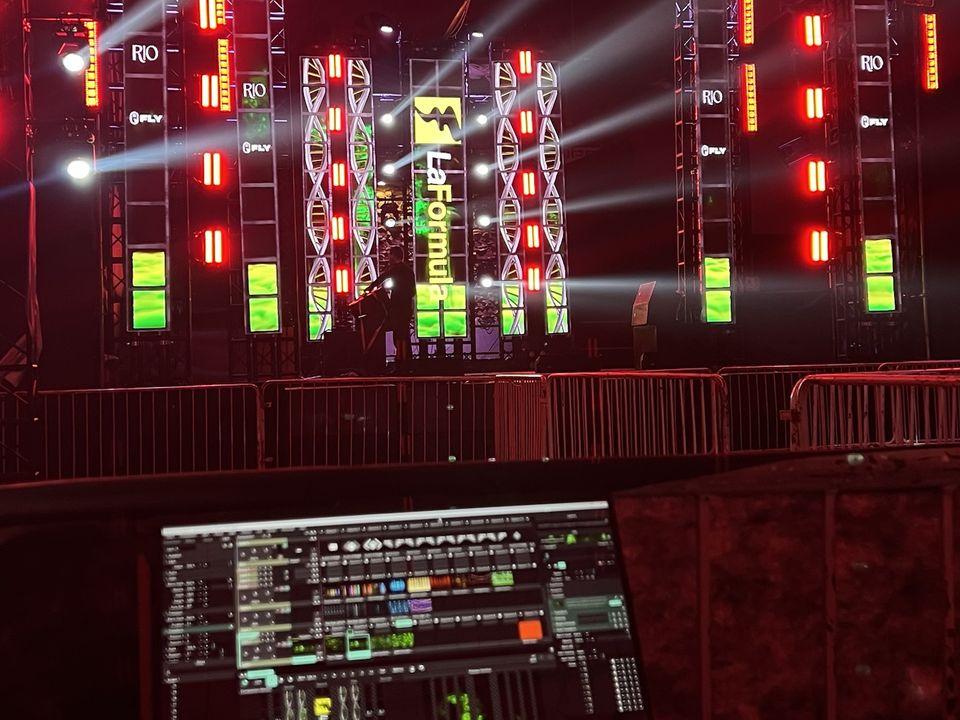 Laptop running Resolume in front of a stage with LED columns and red lights
