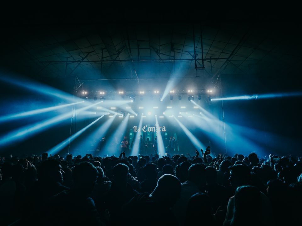 Band playing live with crossing blue beams and the crowd in the foreground